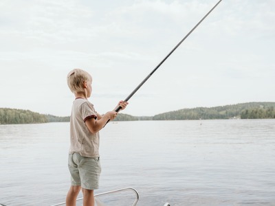 Poika kalastaa rauhallisessa järvimaisemassa